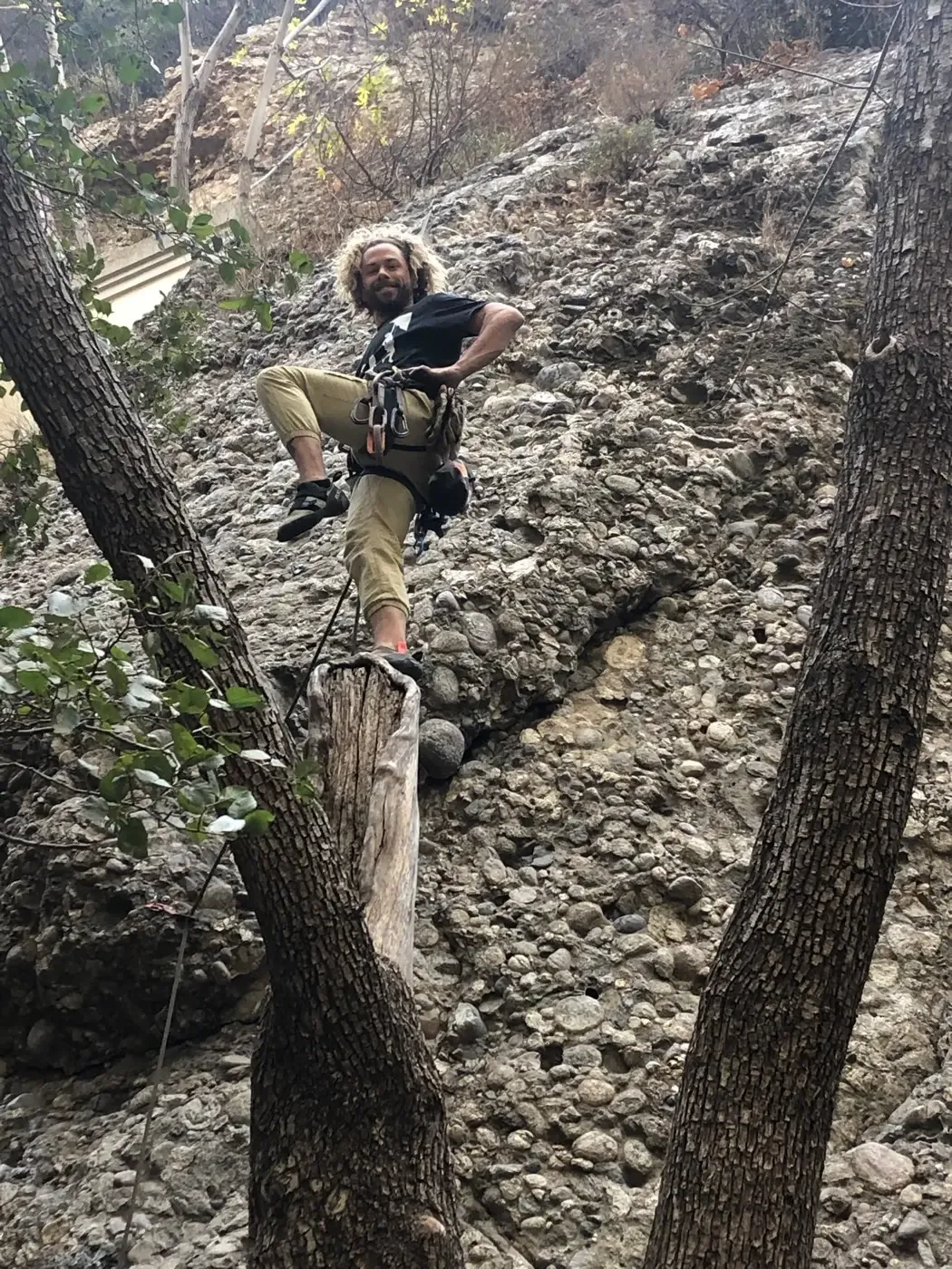 Randy rock climbing in a canyon wearing a harness