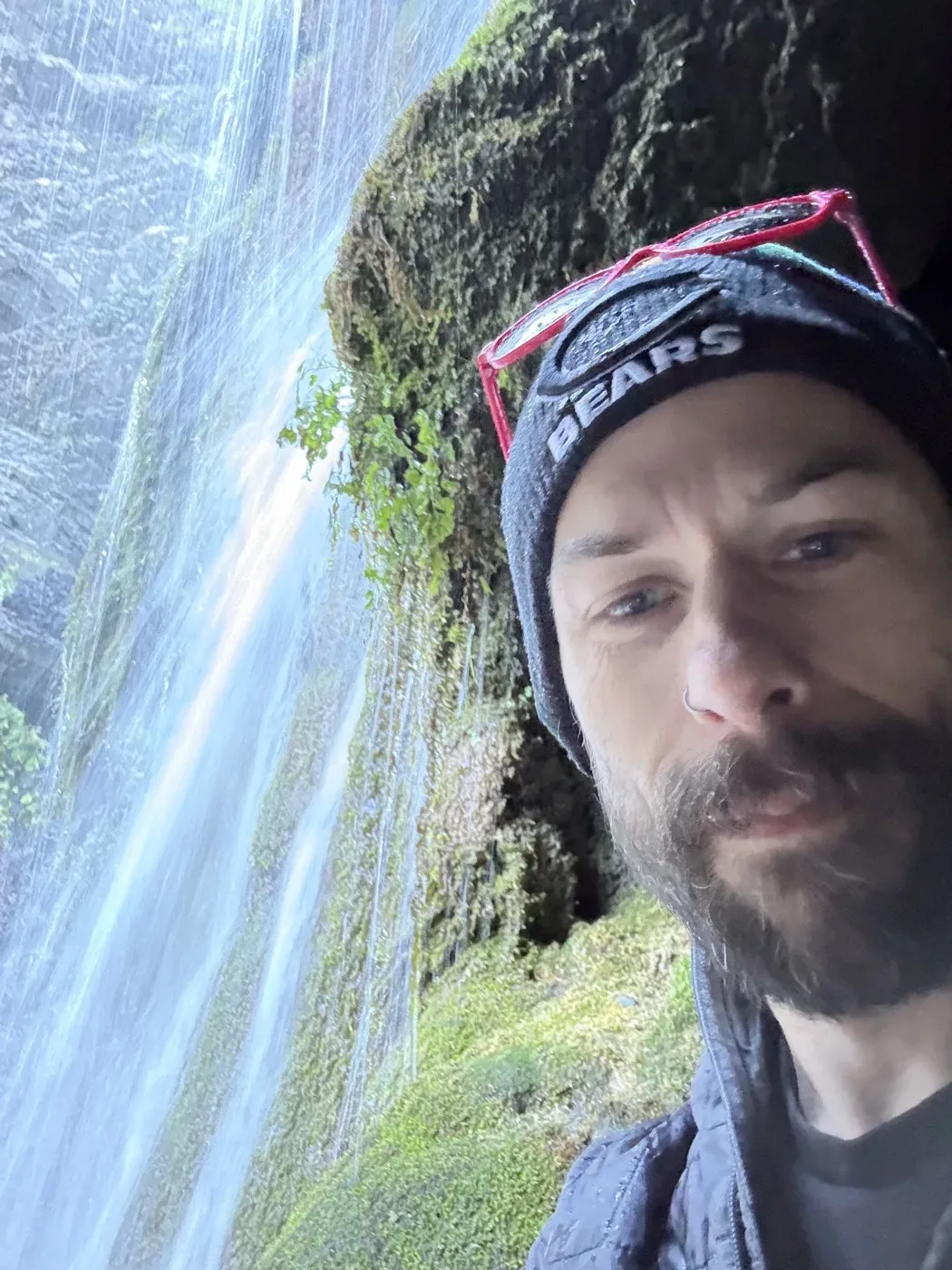 Randy taking a selfie next to a waterfall on a trail